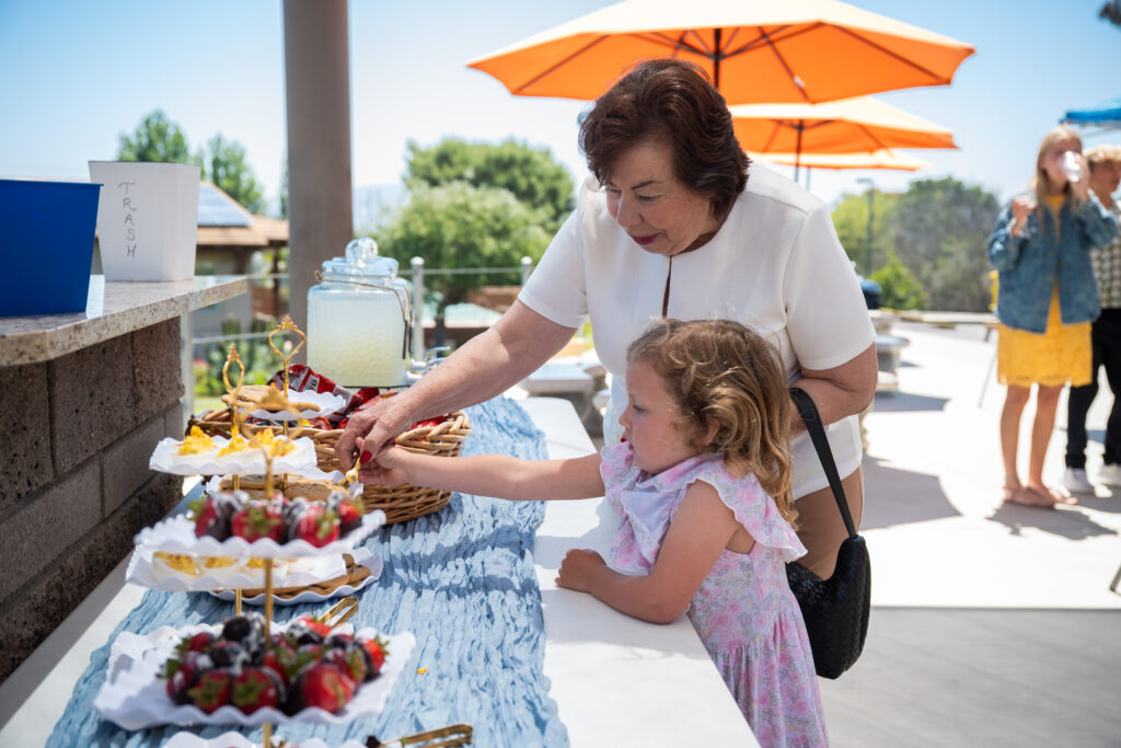 An older woman helps a small child reach a refreshment